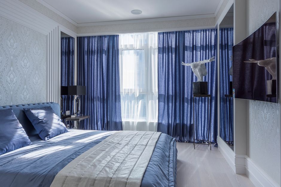 Blauwe gordijnen in luchtige slaapkamerinterieur Blauwe gordijnen in luchtige slaapkamerinterieur